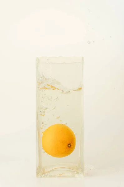 水でいっぱいの透明なガラスの中のオレンジの垂直ショット — ストック写真