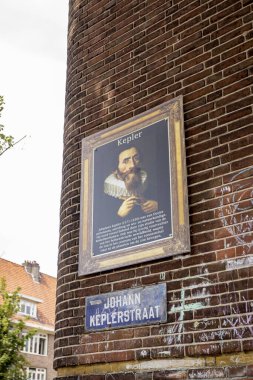 AMSTERDAM, NETHERLANDS - Jun 26, 2021: Street corner with a picture of Johan Kepler in a frame with johankeplerstraat name below clipart