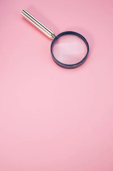 ピンクの背景に拡大鏡の垂直閉鎖 — ストック写真