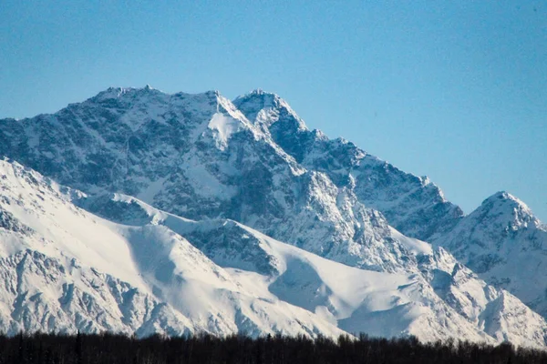 Skalista Góra Pokryta Śniegiem Przeciw Jasnemu Błękitnemu Niebu — Zdjęcie stockowe