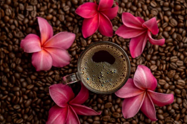 Górny Widok Filiżanki Kawy Powierzchni Pełnej Ziaren Kawy Różowych Kwiatów — Zdjęcie stockowe