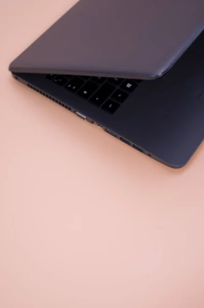 Eine Vertikale Nahaufnahme Eines Schwarzen Laptops Auf Einem Ästhetischen Pfirsichhintergrund — Stockfoto