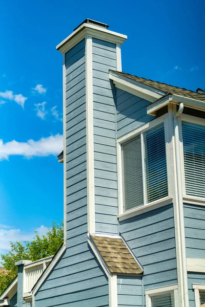 晴れた日には明るい青空の下で長い煙突のある木造住宅の垂直ショット — ストック写真