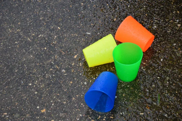 Las Coloridas Tazas Plástico Sobre Asfalto Húmedo — Foto de Stock