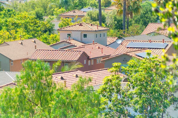 空中拍摄的棕色瓦屋顶房屋 上面有太阳能电池板 周围环绕着生机勃勃的绿树 — 图库照片
