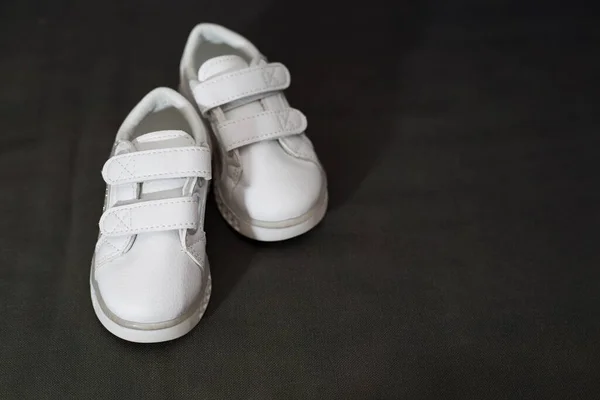 Een Paar Kleine Witte Sportschoenen Een Zwarte Zijden Doek Achtergrond — Stockfoto