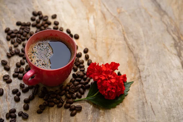 Filiżanka Kawy Fasoli Drewnianym Stole Czerwonymi Kwiatami — Zdjęcie stockowe