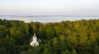 Aerial view to the historic small chapel with the thatched roof and wooden top of the bell tower on the coastal cemetery in Hiiumaa island, Estonia clipart