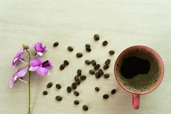 Górny Widok Filiżanki Kawy Purpurowymi Kwiatami Paloną Fasolą Powierzchni — Zdjęcie stockowe