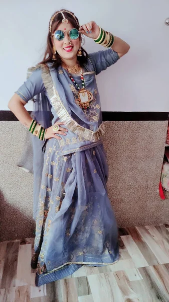 一个身穿传统莎丽服的快乐的印度女孩戴着蓝色太阳镜摆姿势 — 图库照片