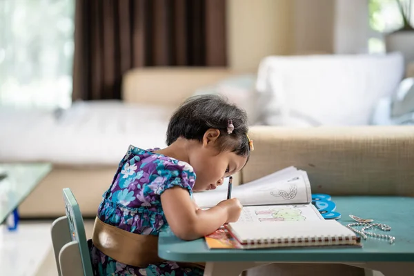 一个可爱的亚洲女孩在家里的笔记本上写字 — 图库照片