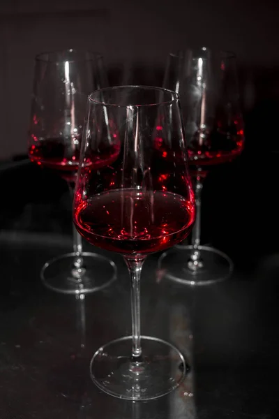 三杯红葡萄酒在昏暗的光线下垂直拍摄的照片 — 图库照片