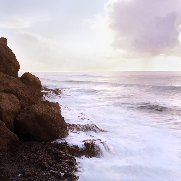 푸르스름 바닷가의 바위에 부딪치는 파도의 — 스톡 사진