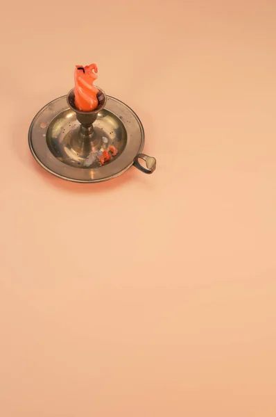 一种橙色的 融化的小烛台 带有一个金属夹子 隔离在米色的背景上 没有文字的空间 — 图库照片