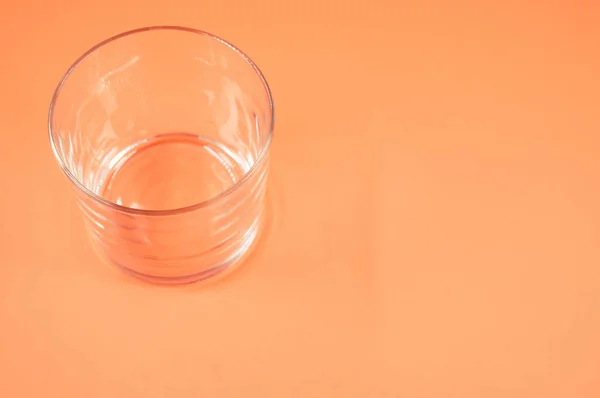 Kaca Minum Kosong Diisolasi Pada Latar Belakang Oranye Dengan Ruang — Stok Foto