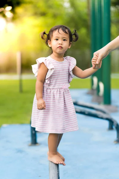 晴れた日に緑豊かな公園でポールに立ってかわいい東南アジアの幼児の垂直ショット — ストック写真