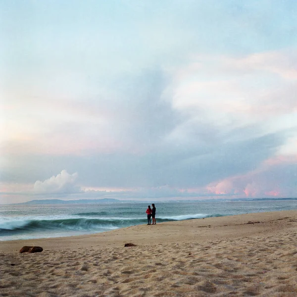 Una Foto Una Pareja Pie Playa Mirando Las Olas — Foto de Stock