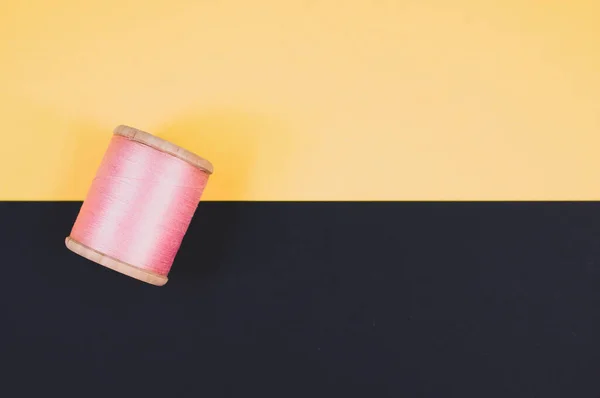 米黄色和黑色背景上缝制的粉红线 — 图库照片
