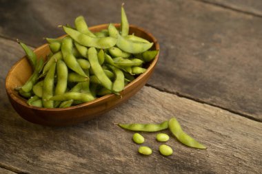A closeup of a bowl of fresh edamame beans on a wooden table clipart