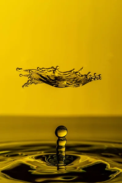 黄色の背景に水が飛び散る美しいショットと空気中の滴 — ストック写真