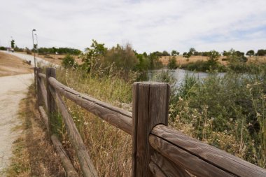 Brown wooden fence with a pond in the background clipart