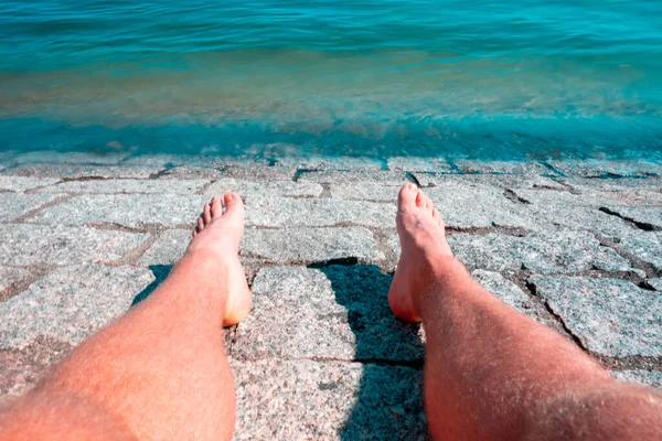 鮮やかな暖かい太陽の下で日焼け白人男性の足の前で美しい澄んだ青い海 — ストック写真