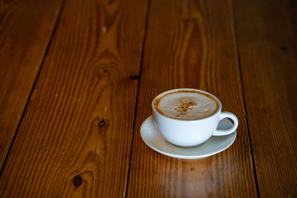 カフェで木製のテーブルの上に泡のカプチーノのカップのクローズ — ストック写真