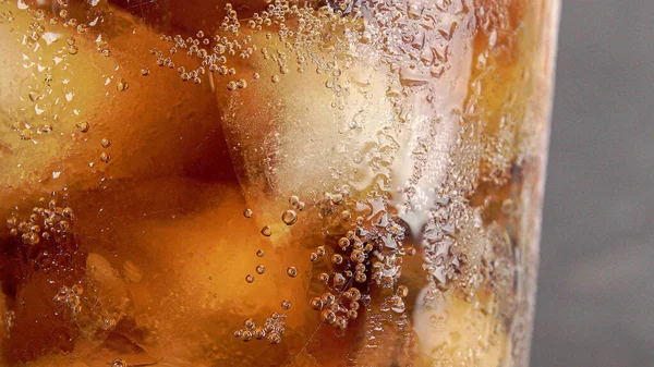 一杯带有饮料 冰块和气泡的湿杯子的特写镜头 — 图库照片