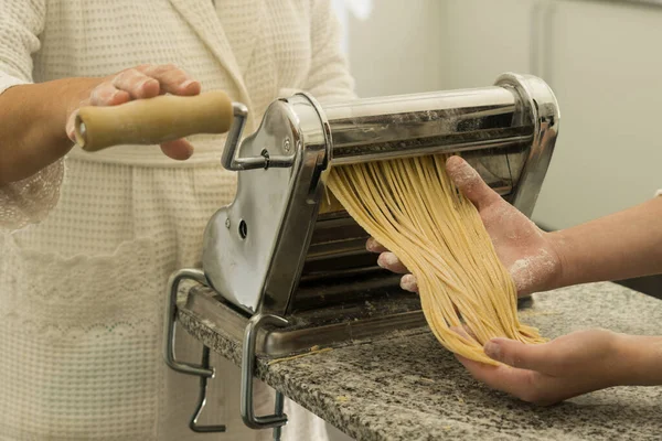 Chef rodando la masa con una máquina de pasta. máquina para hacer pasta.