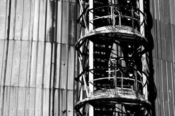 Strzał Skali Szarości Metalowej Wieży Przy Ścianie Zbiornika Oleju — Zdjęcie stockowe