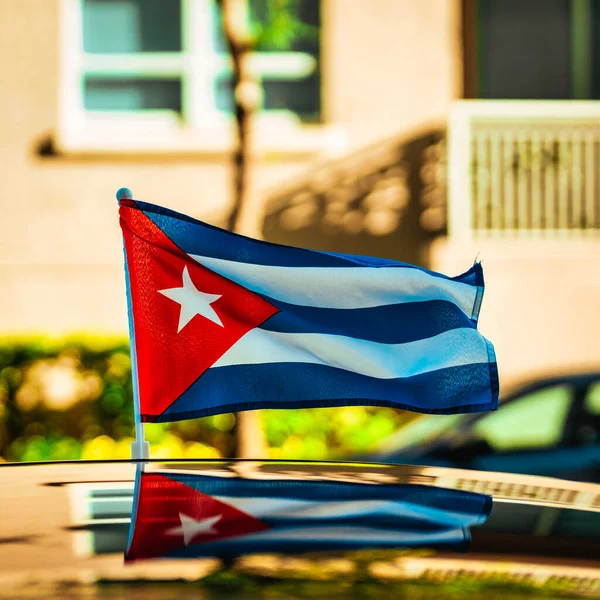 在阳光灿烂的街道上 古巴国旗在车顶上迎风飘扬 车顶下有倒影 — 图库照片