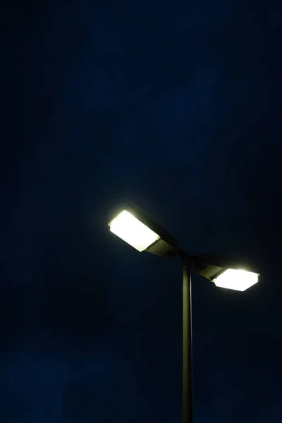 夜の曇り空の下で街灯の垂直ショット — ストック写真