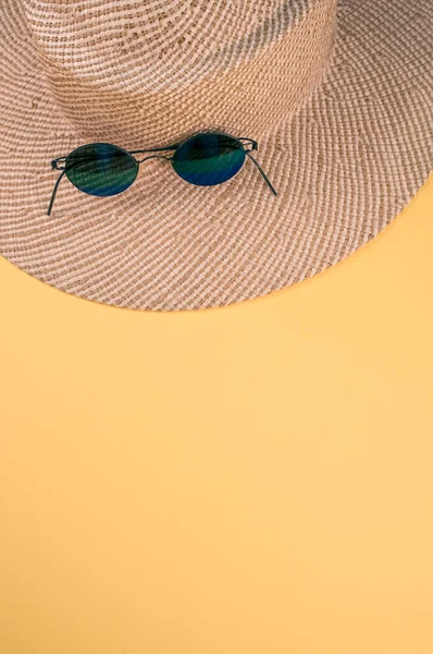 Tiro Vertical Chapéu Palha Óculos Sol Uma Superfície Amarela — Fotografia de Stock