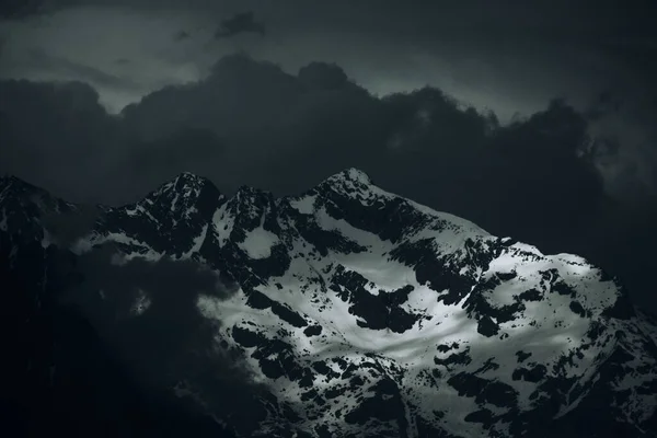 Krajobraz Skalistych Gór Pokryty Śniegiem Pod Ciemnym Zachmurzonym Niebem — Zdjęcie stockowe