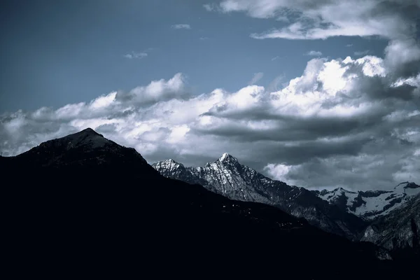 Kara Bulutlu Bir Gökyüzünün Altında Karla Kaplı Kayalık Dağlar — Stok fotoğraf