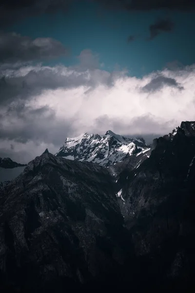 Colpo Verticale Montagne Rocciose Coperte Neve Sotto Cielo Buio Nuvoloso — Foto Stock