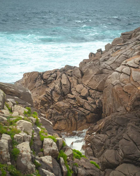 悲観的な日に泡立つ海と岩のビーチの垂直ショット — ストック写真