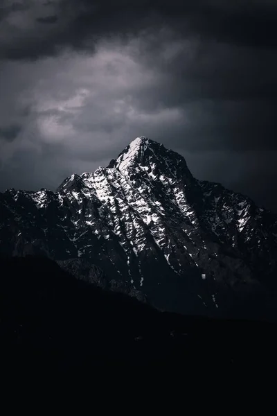 Kara Bulutlu Bir Gökyüzünün Altında Karla Kaplı Kayalık Dağların Dikey — Stok fotoğraf