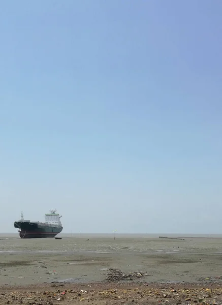 澄んだ青い空の下 浅い海に一人で航海する巨大な船の垂直ショット — ストック写真