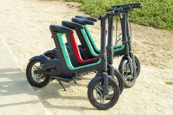 A row of electric bikes on the ground in a park