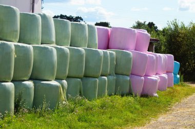 Hermetically wrapped in polyfoil, hay is ensiled as winter fodder on a farm. clipart