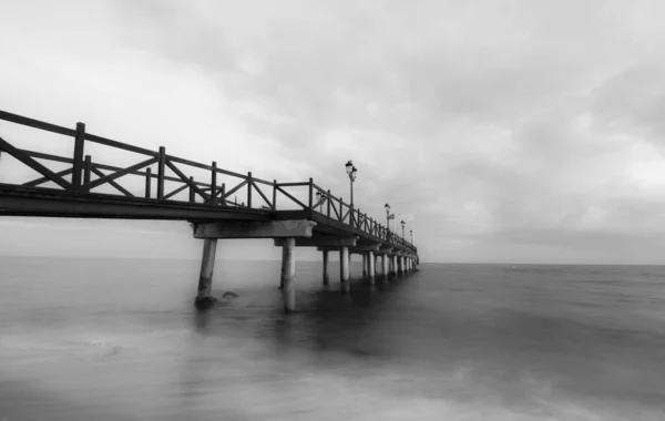 Graustufenaufnahme Einer Seebrücke Über Dem Meer Mit Langzeitbelichtung Unter Bewölktem — Stockfoto
