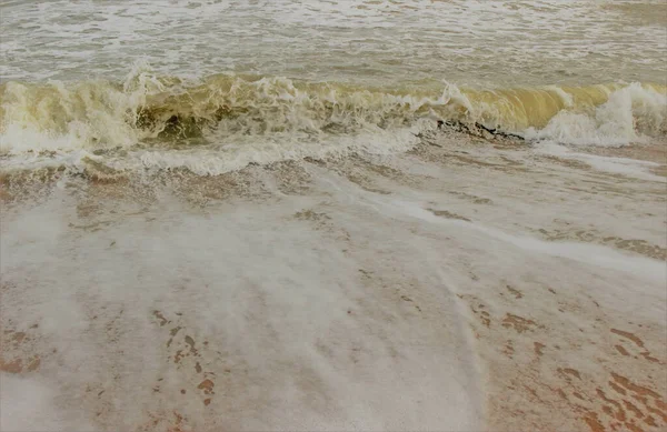 砂に打ち寄せる小さな海の波の逆流はほぼ白い表面を作り出します — ストック写真