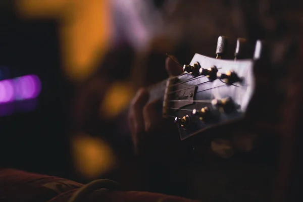 一个男人在模糊的背景下弹奏吉他的选择性镜头 — 图库照片