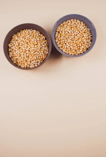 薄い茶色の背景に隔離されたボウルにトウモロコシの穀物の垂直ショット — ストック写真