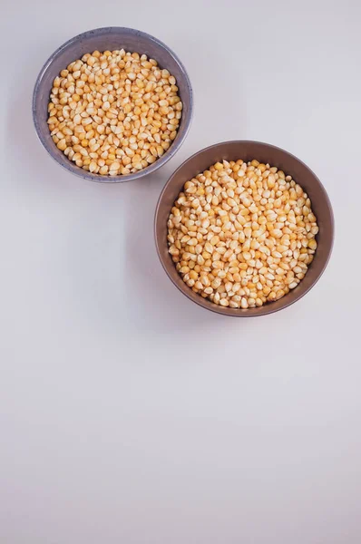 薄い灰色の背景に隔離されたボウルにトウモロコシの穀物の垂直ショット — ストック写真