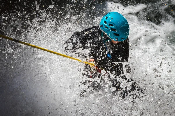 A person with a blue helmet rafting in Corsica, France with water splashing everywher