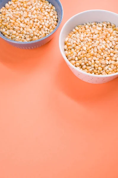 オレンジの背景に隔離されたボウルにトウモロコシの穀物の垂直ショット — ストック写真