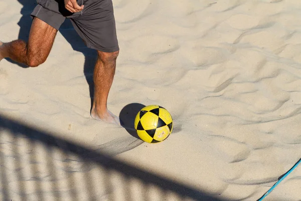 一个穿短裤在海滩上打足球排球的男人 — 图库照片