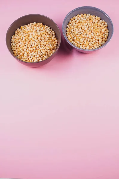 ピンクの背景に隔離されたボウルにトウモロコシの穀物の垂直ショット — ストック写真